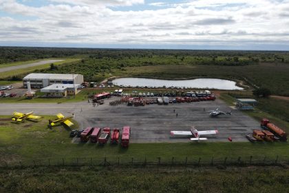 Vista aérea de uma base de combate a incêndios com aviões, caminhões e equipes de emergência reunidos.