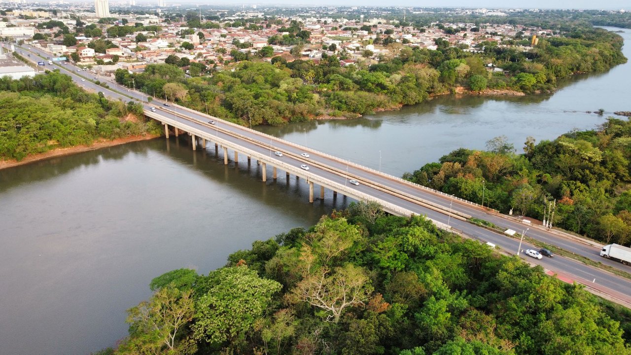 Vista aérea de uma ponte sobre um rio cercado por vegetação em Cuiabá, Mato Grosso.