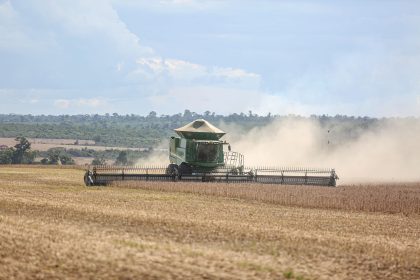 Colheitadeira trabalhando em uma extensa plantação de soja.